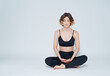 © SHOTPRIME STUDIO - A woman is meditating on a light background with her legs crossed on the floor