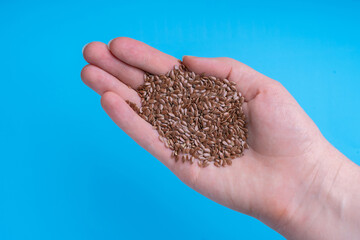 Flax seeds in a female palm on a blue background