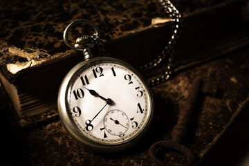 Open pocket watch and a stack of books.