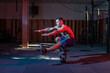 Muscular man squat with one leg while standing on a kettlebell in neon red blue gradient light. Balance training