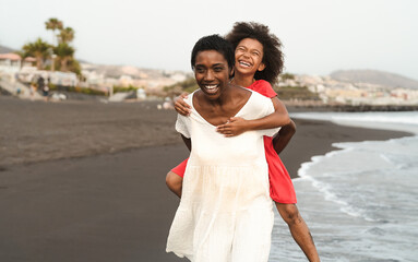 Wall Mural - Happy African family on the beach during summer holidays - Afro American people having fun on vacation time - Parents love and travel lifestyle concept