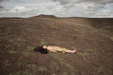 Conceptual Portrait Of A Girl In Golden Dress Laying Peacefuly On Lava Rocks In Iceland