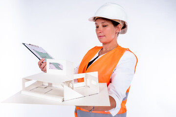 Poster - Woman architect with building layout. Portrait of architect on a white background. Architect bureau employee. Girl in uniform of a builder. Concept - architectural planning. House project creation