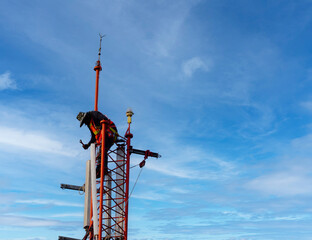 Engineer maintenance on telecommunication tower doing ordinary maintenance and control to antenna for communication, 3G, 4G and 5G cellular. Cell Site Base Station on blu sky background.