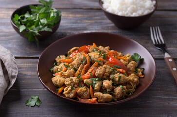 Vegan stew soy meat and vegetables served with boiled rice and herbs on wooden table, selective focus, horizontal. Delicious healthy diet food