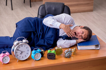 Young male employee sleeping in the office in time management co