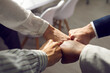 Close up of hands of business partners folding fists together as a symbol of unity. Four people bumping their fists together in an office at a meeting. Concept of trust, friendship and cooperation.