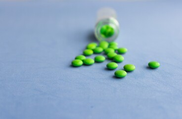 Bottle and scattered pills on color background, top view. Space for text