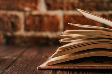 Canvas Print - Opened book on a pile of old books.  Study education concept. Brick backround.