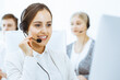 © Iryna - Call center. Group of diverse operators at work. Beautiful woman in headset communicating with customers of telemarketing service. Business concept