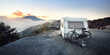 Caravan trailer with a bicycle near mountain lake Lac de serre-poncon in French Alps at sunrise. Golden sunlight, fog. Wanderlust, tourism, landmark, vacations in France. Transportation, RV, lifestyle