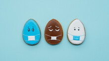 World Pandemic. Easter Quarantine. Holiday Lockdown. Creative Pastry Composition. Blue White Chocolate Brown Gingerbread Egg Cookie With Sad Face In Mask Icing Design Isolated On Light Background.