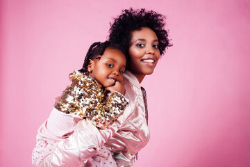 young pretty african-american mother with little cute daughter hugging, happy smiling on pink background, lifestyle modern people concept