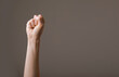 female hand clenched into a fist on a gray background. gesture of fighting, winning or protest. Human hand gesturing sign isolated. Female raised arm presenting popular gesture. copy space