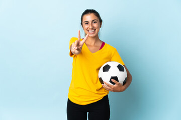 Young hispanic football player woman over isolated on blue background smiling and showing victory sign