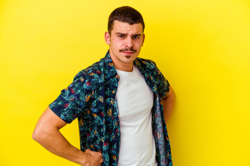 Young caucasian cool man isolated on yellow background frowning face in displeasure, keeps arms folded.