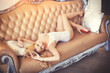 © Anna - A gorgeous blonde girl in white lace lingerie lying on the beige leather couch on the background of a classic interior. A sensual and sexy boudoir portrait.