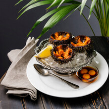 Fresh Opened Sea Urchins On Ice In Silver Bowl With Quail Egg And Soy Sauce On Black Wooden Table