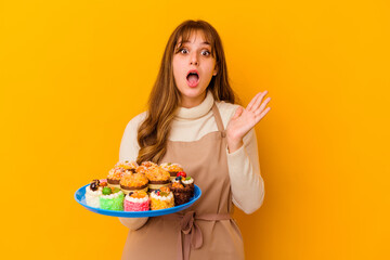 Wall Mural - Young pastry chef woman isolated on yellow background surprised and shocked.