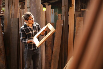 Wall Mural - Young Caucasian carpenter man is making wooden frame in his own garage style workshop for hobby with copy space