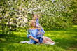 © Elena  - Happy chubby mom and two kids boy and girl in a blooming spring apple orchard on a spring picnic.