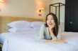 © siraphol - Portrait beautiful young asian woman smile happy relax on bed