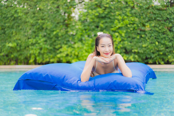 Portrait beautiful young asian woman relax smile around outdoor swimming pool in hotel resort