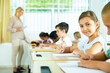 © JackF - Focused girl sitting at desk writing test in classroom full of pupils during lesson