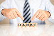 © HNFOTO - Geschäftsmann oder Vertriebler mit dem Schlagwort DANKE als Buchstaben auf Würfeln auf dem Schreibtisch