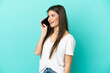© luismolinero - Young caucasian woman isolated on blue background keeping a conversation with the mobile phone