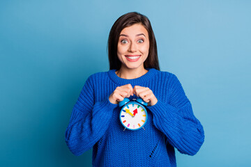 Wall Mural - Photo of young happy joyful smiling excited crazy girl holding clock wear knitted jumper isolated on blue color background