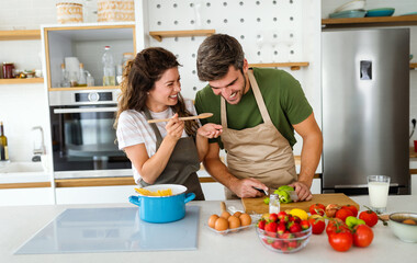 Wall Mural - Happy young couple have fun in kitchen while preparing healthy organic food