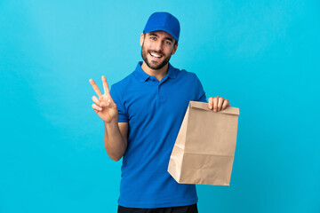 Wall Mural - Delivery man with beard isolated on blue background smiling and showing victory sign