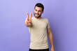 © luismolinero - Young handsome man with beard over isolated background smiling and showing victory sign