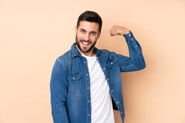 Wall Mural - Caucasian handsome man isolated on beige background doing strong gesture