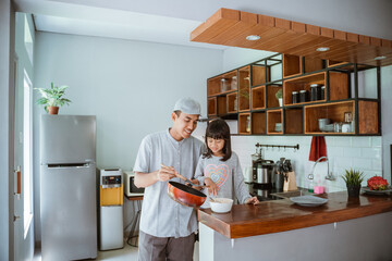 Wall Mural - portrait of happy asian father and daughter cooking together in modern kitchen