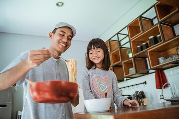 Wall Mural - portrait of happy asian father and daughter cooking together in modern kitchen