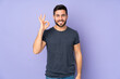 © luismolinero - Caucasian handsome man showing ok sign with fingers over isolated purple background