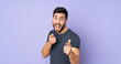 © luismolinero - Caucasian handsome man surprised and pointing front over isolated purple background