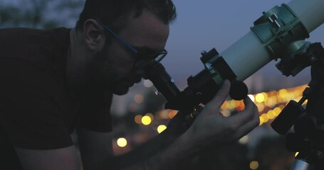 Wall Mural - astronomer with a telescope watching at the stars and moon with blurred city lights in the backgroun