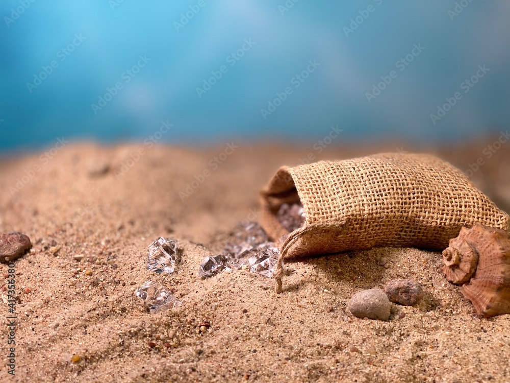Crystals falling out of the jute bag on the sand visible stones and shells - obrazy, fototapety, plakaty 