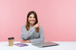 © khosrork - Smiling positive woman advertising agency worker pointing finger away paying attention and showing freespace for your advertising sitting at workplace. Indoor studio shot isolated on pink background