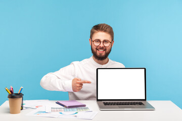 Wall Mural - smiling positive man office worker with beard pointing finger at laptop with empty screen, showing h