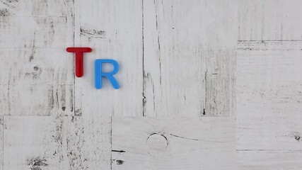 Fototapete - Word - Travel - in bright colorful letters arranged diagonally on grey wood background with corner borders with a multicolored alphabet. Stop motion, top view