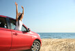 © New Africa - Happy young woman leaning out of car window on beach, space for text. Summer trip