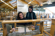 Students Weaving With Loom In Textile Workshop