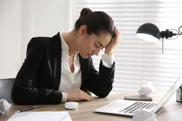 Stressed and tired young woman at workplace