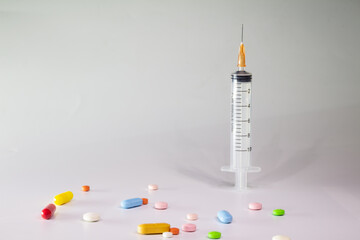 Wall Mural - Colored pills on a white background with free space to write. Subcutaneous needle syringe. Concept of legal drug use