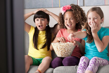 Three Girls Watching Tv Eating Popcorn