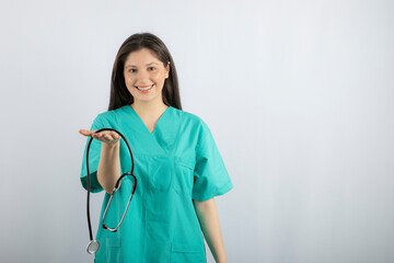 Portrait of female nurse showing stethoscope on white background